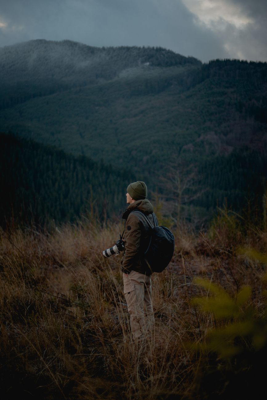 Travel photojournalist carrying camera equipment in nature